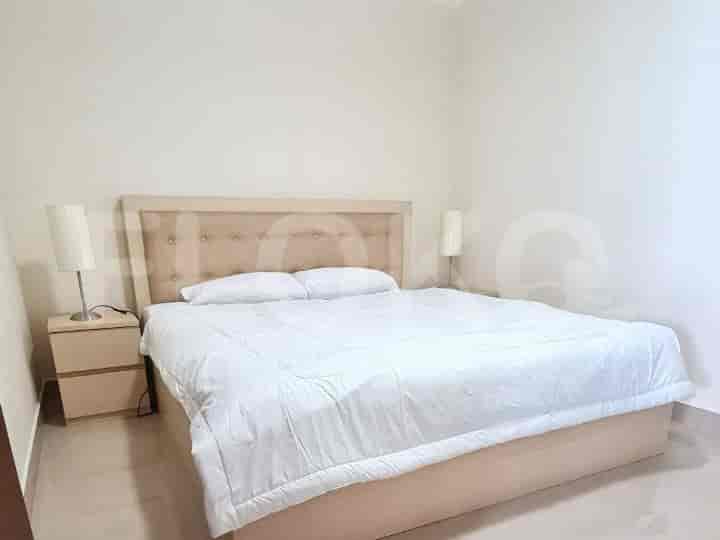 A well-lit bedroom featuring a bed, side tables, and lamps.