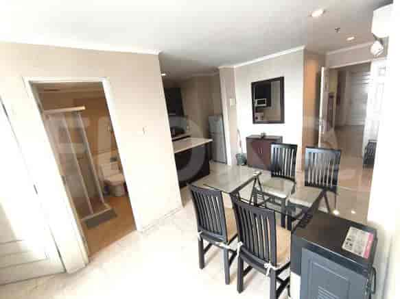A combined dining and kitchen area with a glass table and a small kitchen with a refrigerator.
