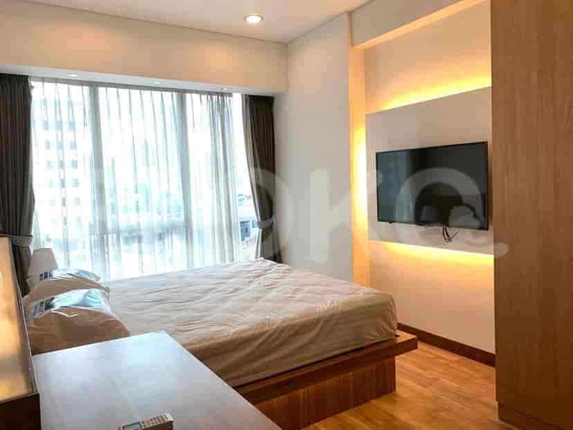 Kamar tidur dengan tempat tidur, gorden, dan TV yang dipasang di dinding.