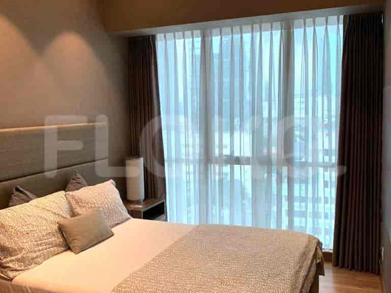 Kamar tidur dengan tempat tidur, meja samping tempat tidur, gorden, dan jendela besar.