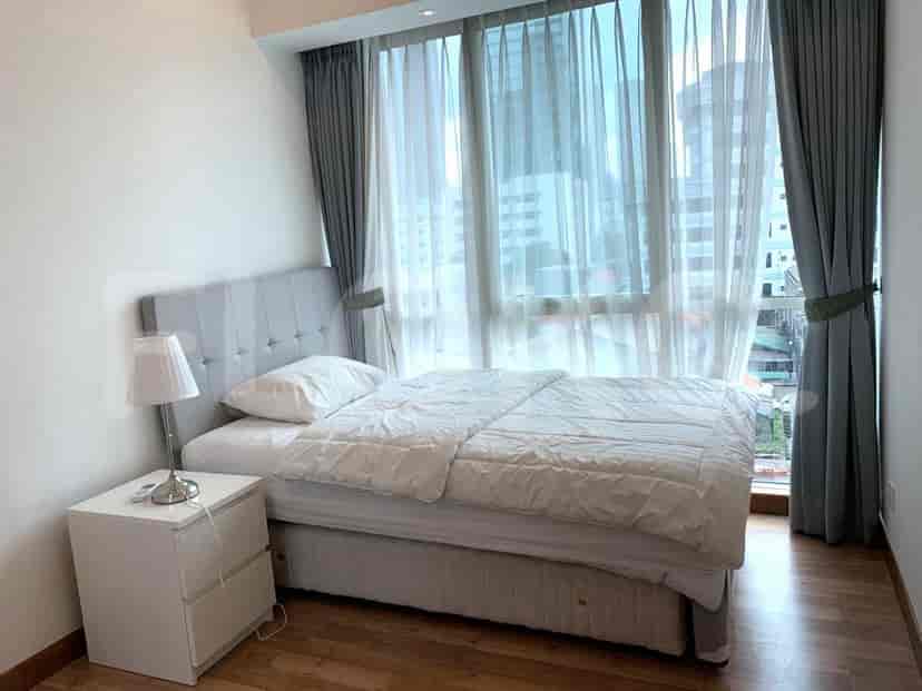 Kamar tidur dengan tempat tidur, meja samping tempat tidur, lampu, dan jendela besar.