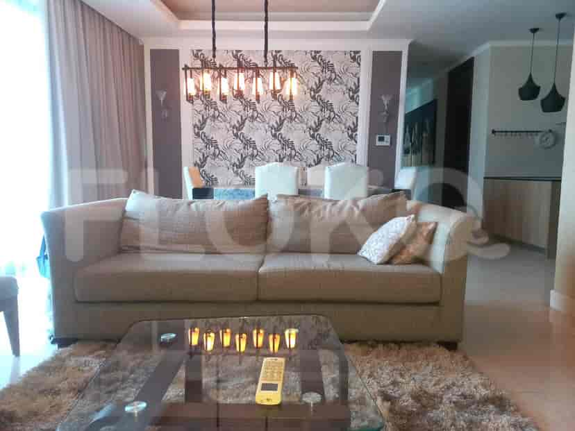 Living room featuring a light-colored sofa, glass coffee table, and dining area in the background.