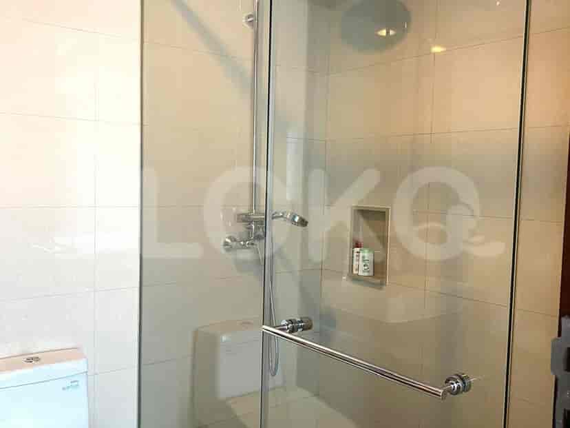 Bathroom with a shower, toilet, and beige tiles.