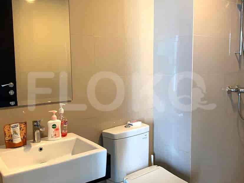 Bathroom with a sink, toilet, and beige tiles.