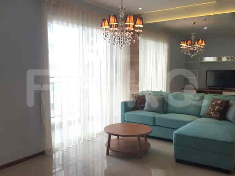 Spacious living room with L-shaped turquoise sofa, round coffee table, and chandeliers.