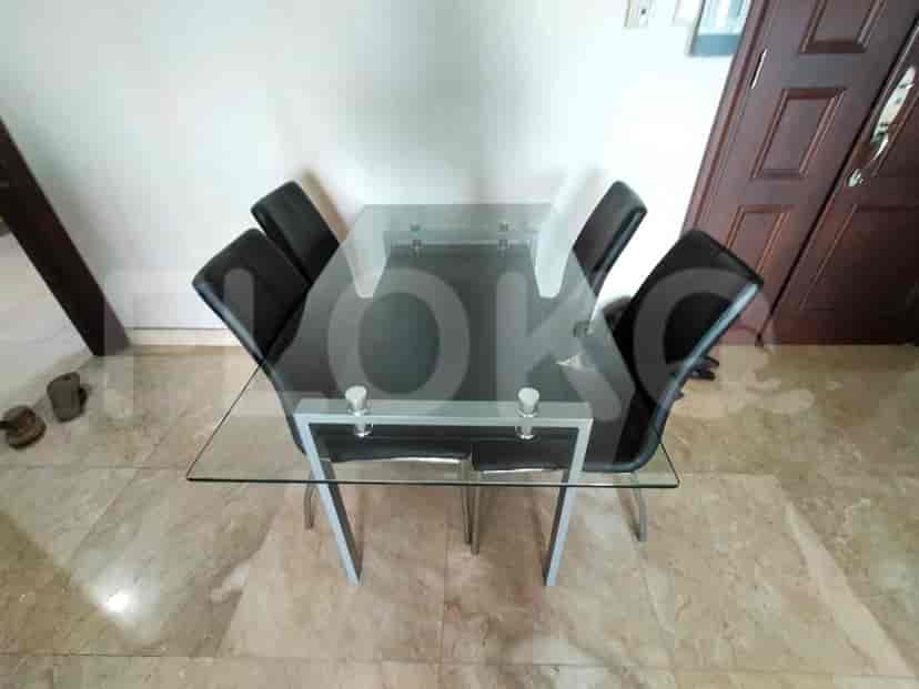 A dining table with glass top and black chairs.