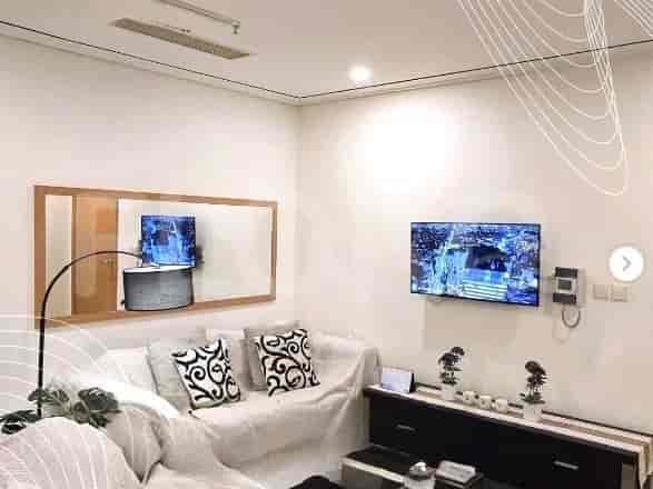 A modern living room with a sofa, TV, and mirror.