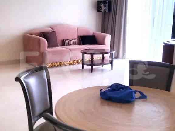 A living room with a pink sofa, round wooden table, and two chairs.