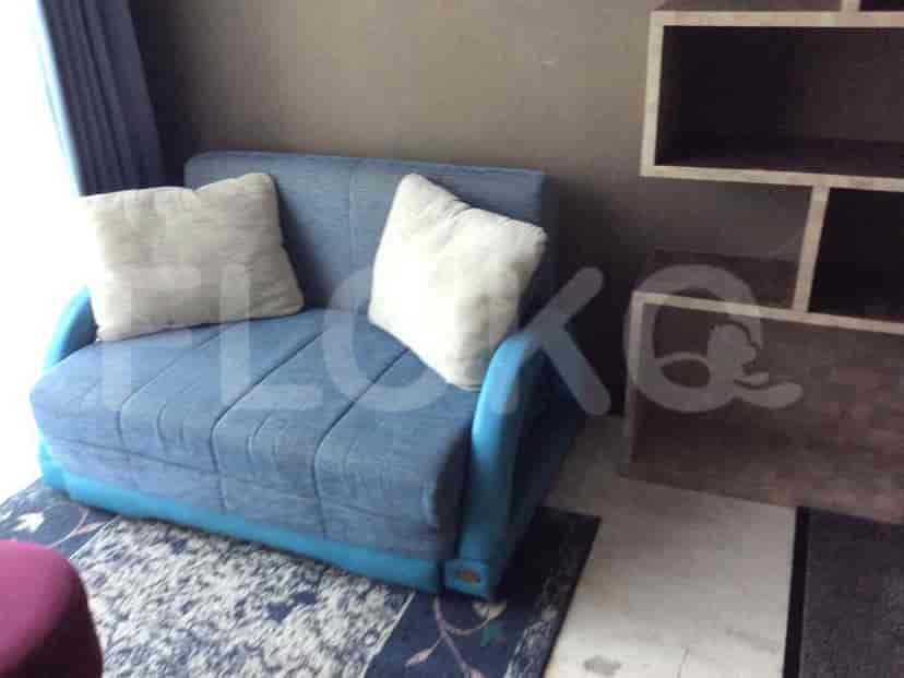 Blue loveseat with pillows, wooden shelf, and rug.