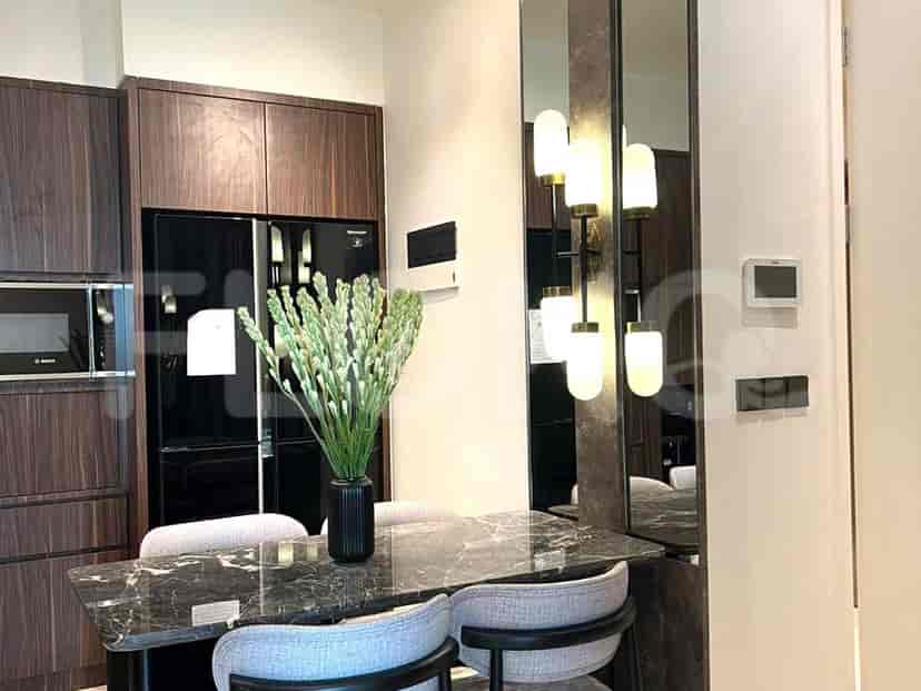 Area makan dengan meja marmer dan dapur dengan lemari es.
