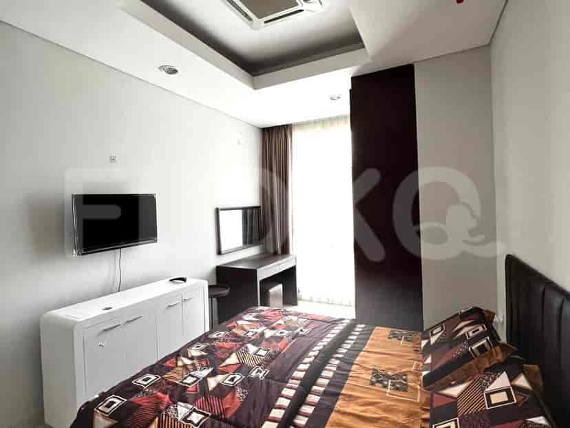 A bedroom with a bed, TV, dresser, and dark accent wall.