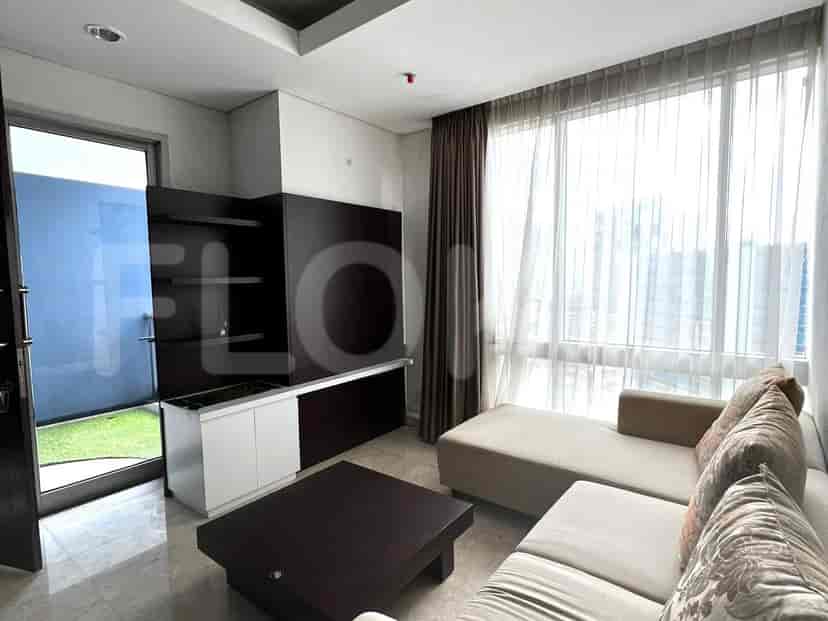 Modern living room featuring a sectional sofa, dark wood entertainment center, and large window with curtains.