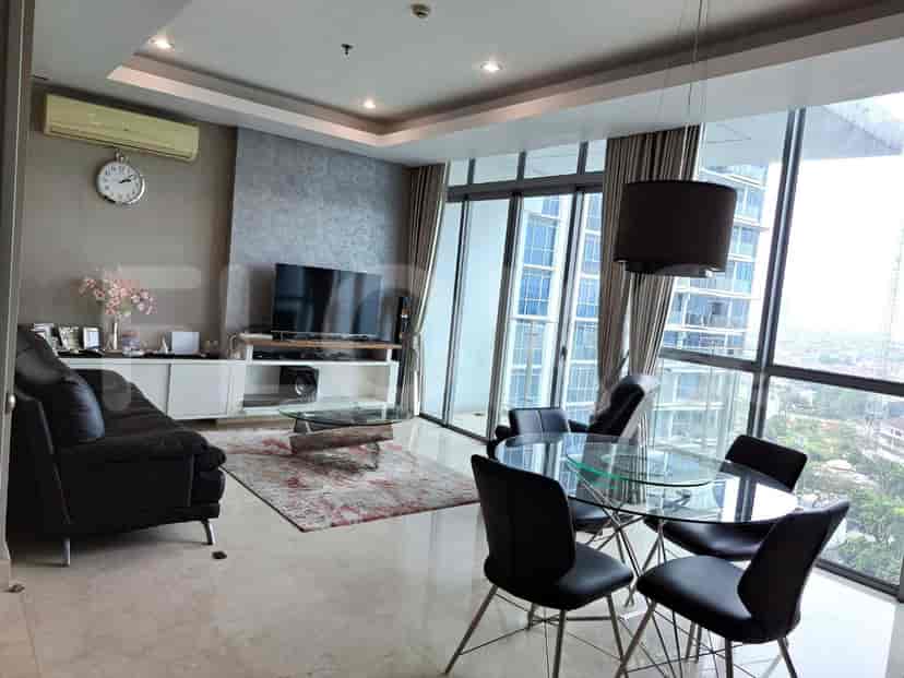 Modern living room with a black sofa, glass dining table, and large windows.