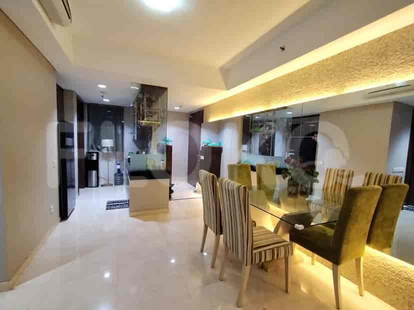 A dining area with a glass table, chairs, and a kitchen in the background.