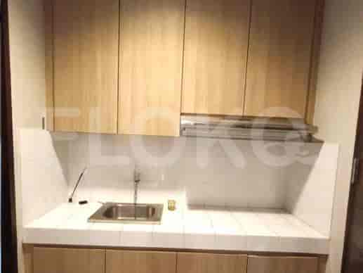 A compact kitchenette with wooden cabinets, a stainless steel sink, and a range hood.