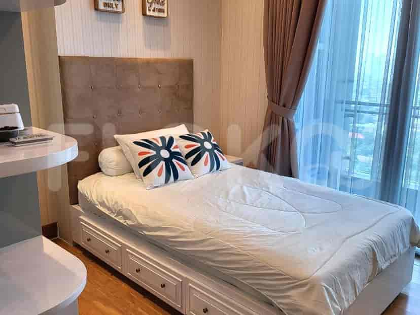 A bedroom with a bed featuring an upholstered headboard and large windows.