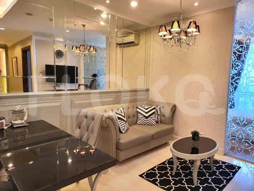A living room featuring a tufted sofa, mirror wall, and a chandelier.