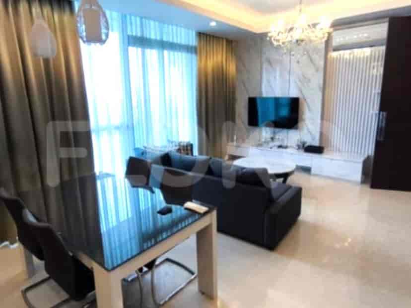 Luxurious living area featuring a modern grey sofa, dining table, and a view through large windows.