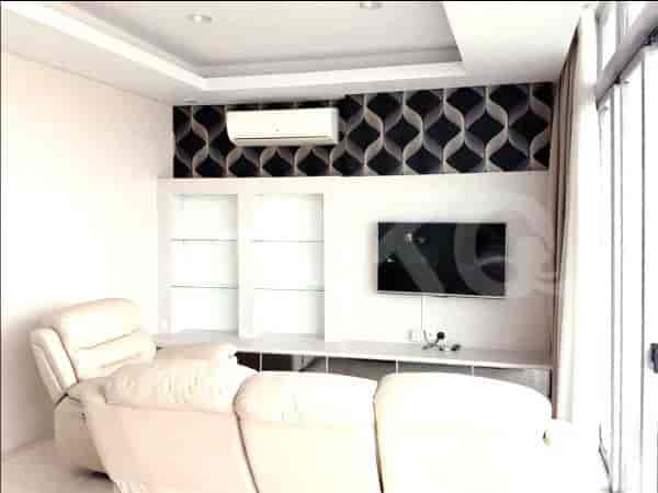 Ruang tamu dengan sofa recliner putih, TV, dan panel dinding dekoratif.