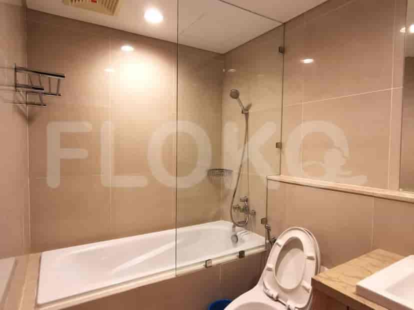 A bathroom with a bathtub, glass shower screen, and tiled walls.