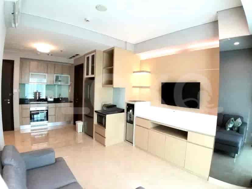 A modern apartment living area with a sofa, kitchen, and city view.