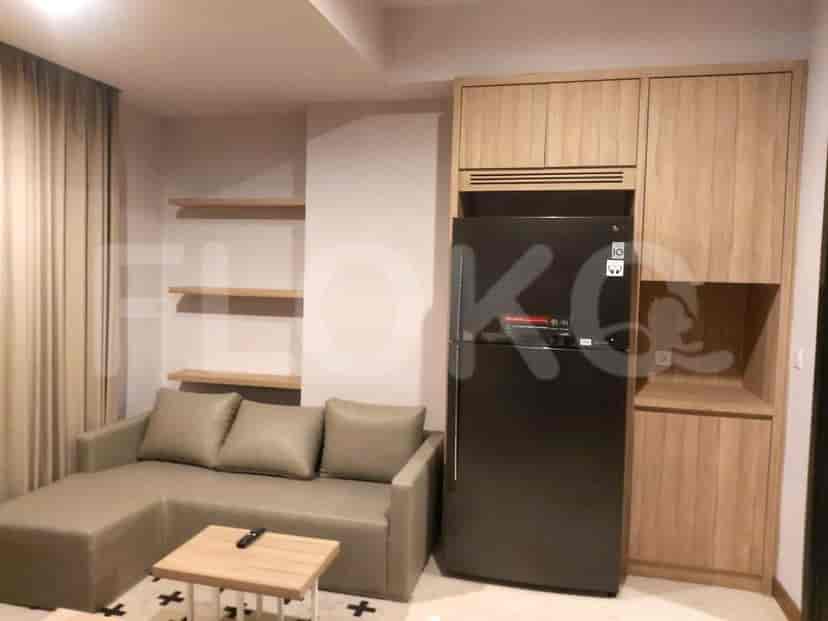 Modern living room with a grey L-shaped sofa, wooden shelves, and a refrigerator.