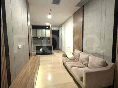 A modern living area with a sofa, kitchen area, and hallway.