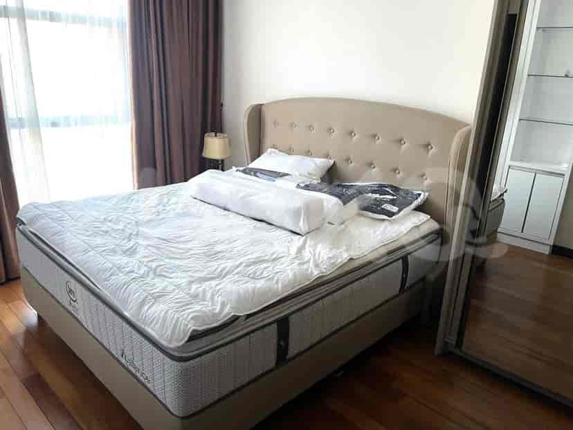 A bedroom with a large bed, window, and curtains.