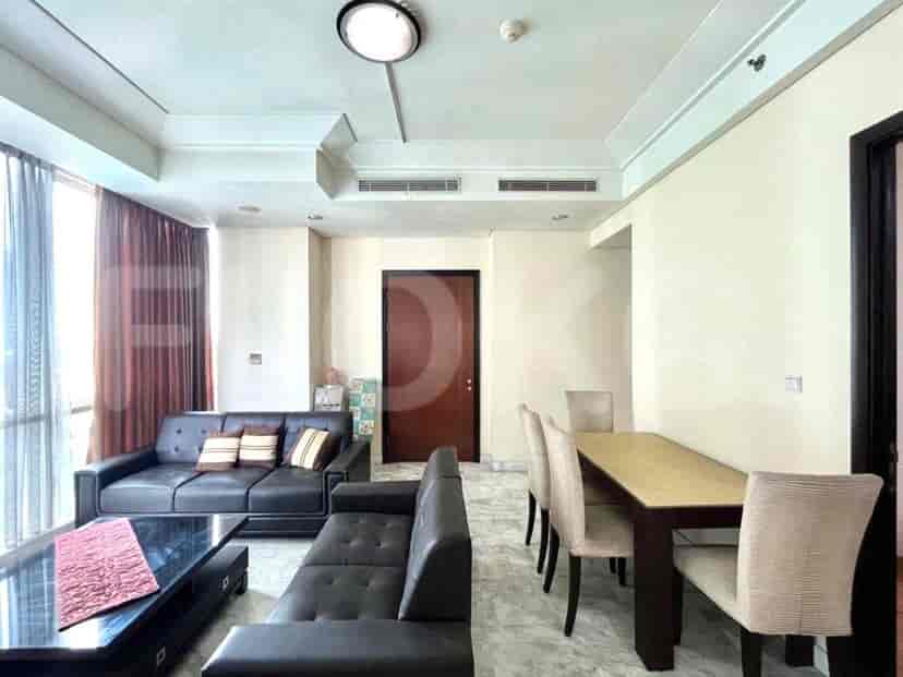 Living area with a black leather sofa, glass coffee table, dining set, and large windows.