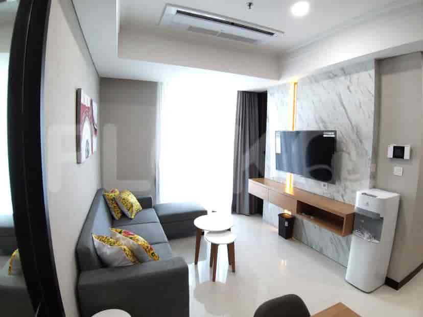 Ruang tamu modern dengan sofa berbentuk L, TV pintar, dan dinding aksen marmer.