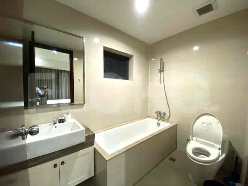 Modern bathroom with a bathtub, mirror, and toilet.