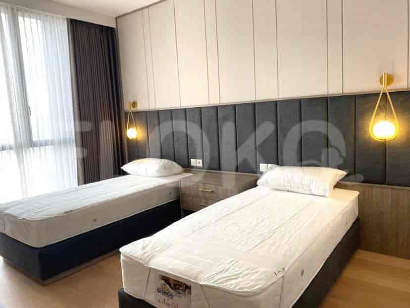 Kamar tidur dengan tempat tidur kembar, meja samping tempat tidur, dan pencahayaan yang bergaya.
