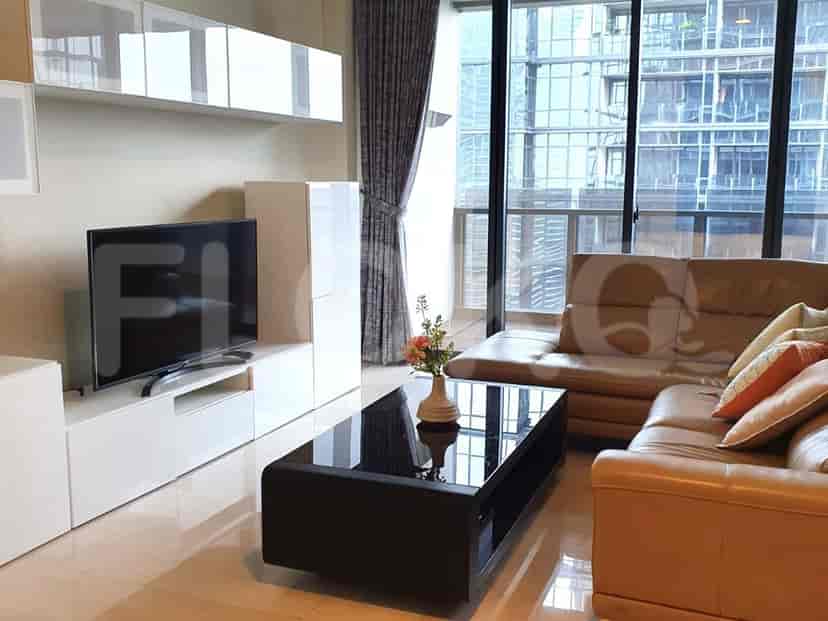 Ruang tamu modern dengan sofa kulit, TV, dan meja kopi kaca.