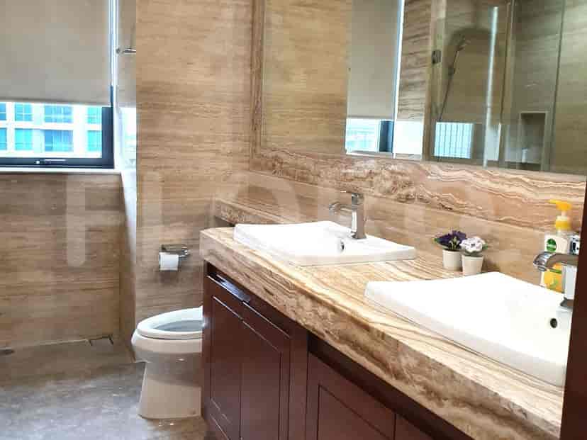 Kamar mandi dengan dinding marmer, wastafel ganda, dan toilet.