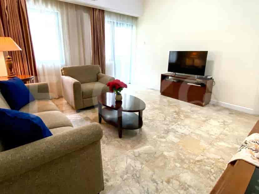 Ruang tamu yang menampilkan sofa abu-abu, TV di lemari kayu, dan lantai marmer.