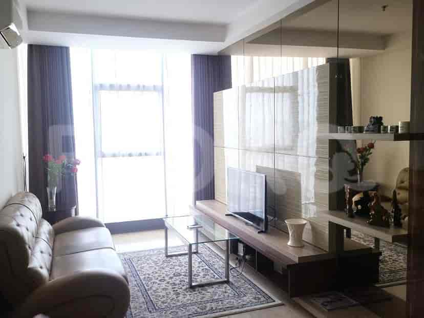 Living room with large windows, a brown leather sofa, and a TV.