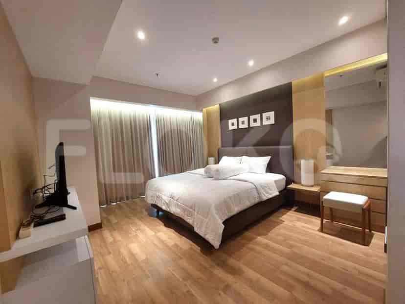 A well-lit master bedroom featuring a large bed, wooden floors, and modern decor.