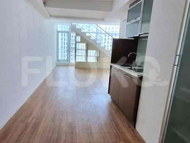 An interior view showcasing a living area with a kitchenette, stairs leading to an upper level, and a large window providing natural light.
