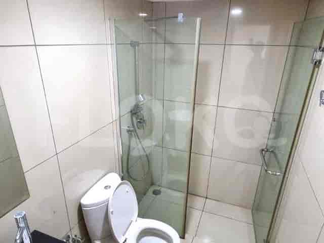 A modern bathroom with a glass shower enclosure, a toilet, and tiled walls.