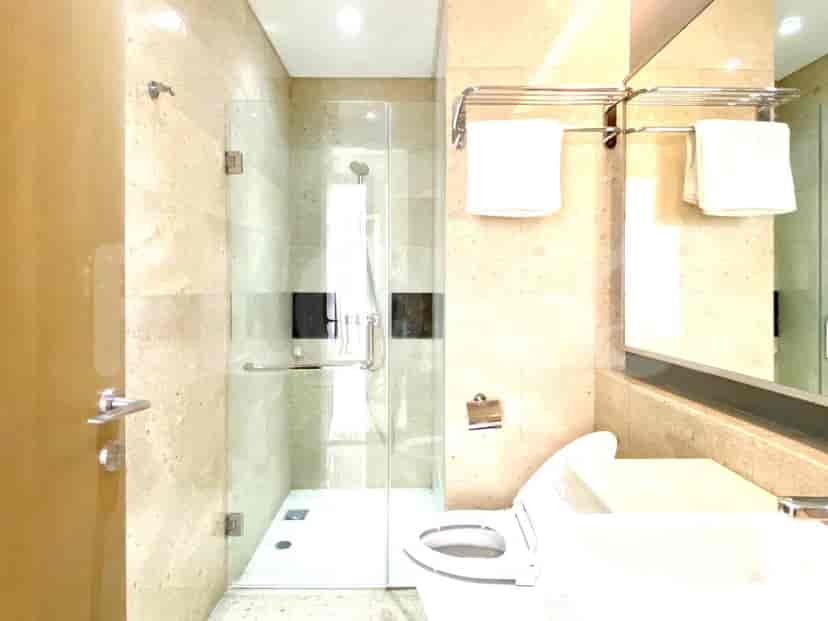 A modern bathroom with a glass shower, marble walls, and a white toilet.