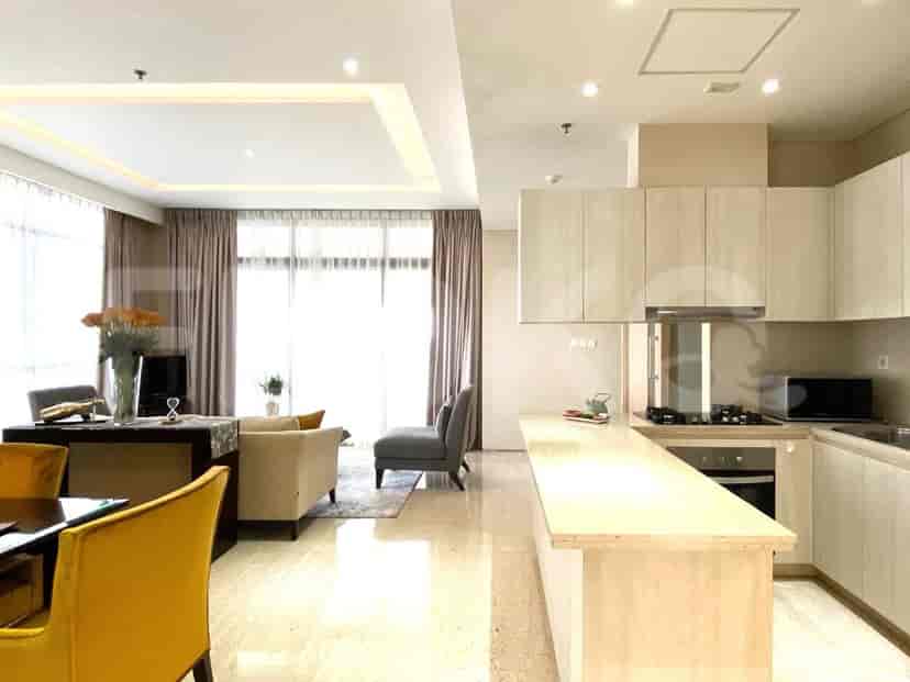 Combined view of the kitchen and living area with a light wooden kitchen island and cream-colored sofa.