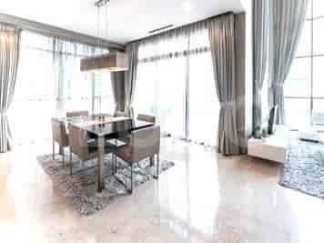A dining room with a glass table, modern chairs, and large windows with sheer curtains.