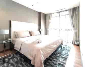 A modern bedroom with a king-size bed, and floor-to-ceiling windows.