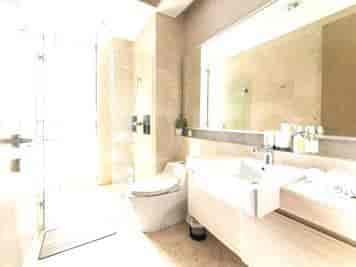 A modern bathroom with a large mirror, toilet, and sink.