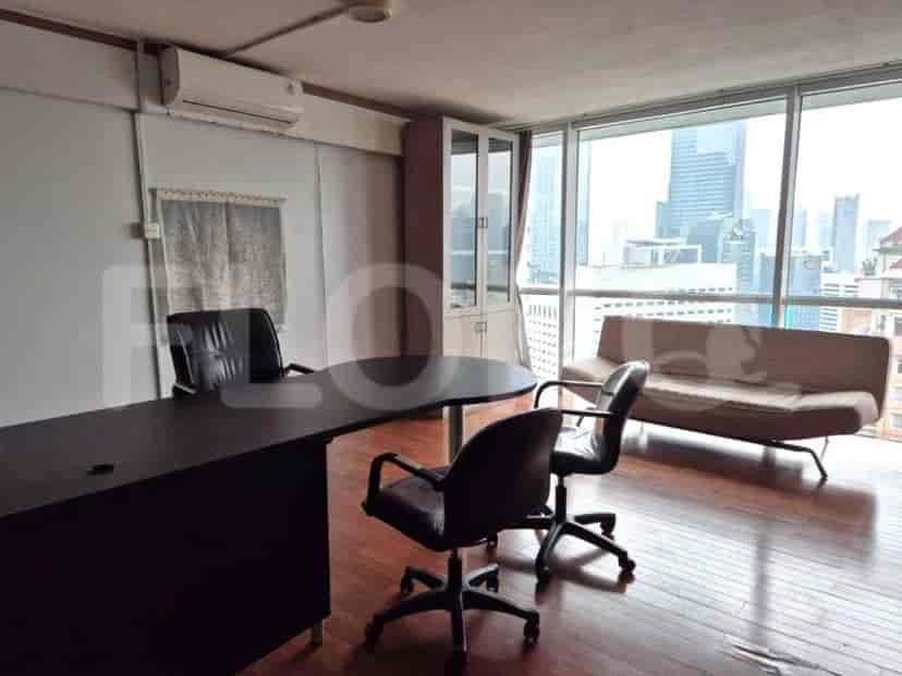 An office with a desk, chairs, and a city view.