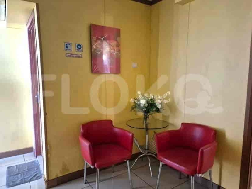 A waiting area with red chairs, a glass table, and a flower vase.