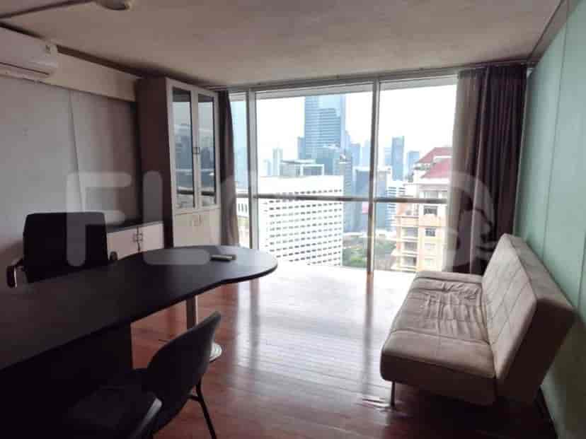 An office with a large desk, chairs, a cabinet, a couch, and a city view.