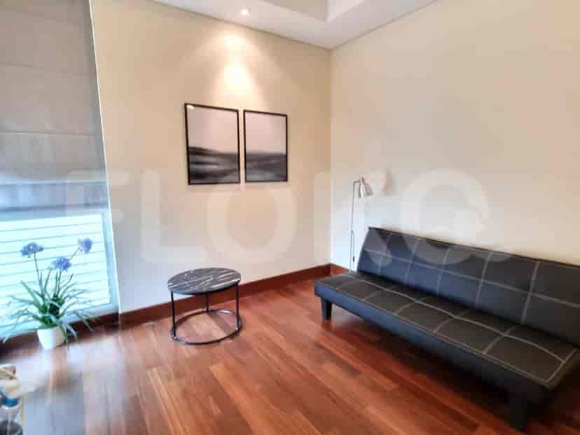 A well-lit living area featuring a black futon sofa, round side table, and artwork.