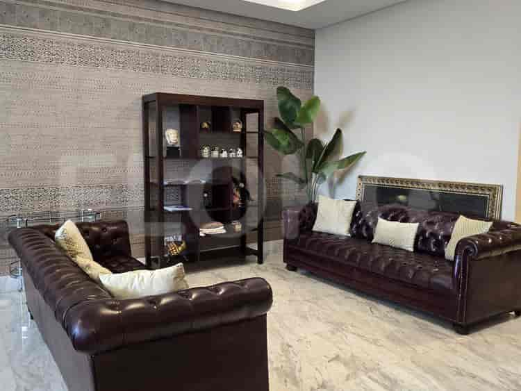 Living room with two leather sofas, a bookshelf, and a large plant.
