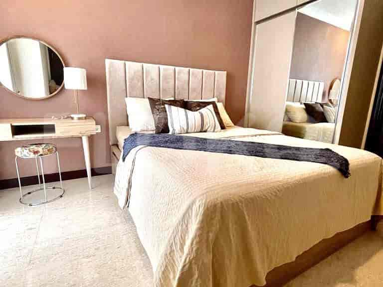 A bedroom with a bed, desk, mirror, and a neutral color palette.